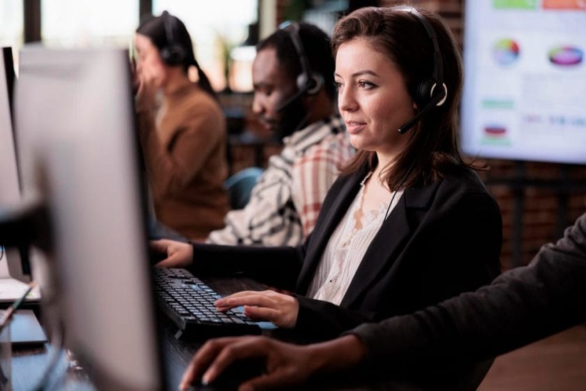 Female agent using call center CRM software to manage and analyze customer data on a computer.